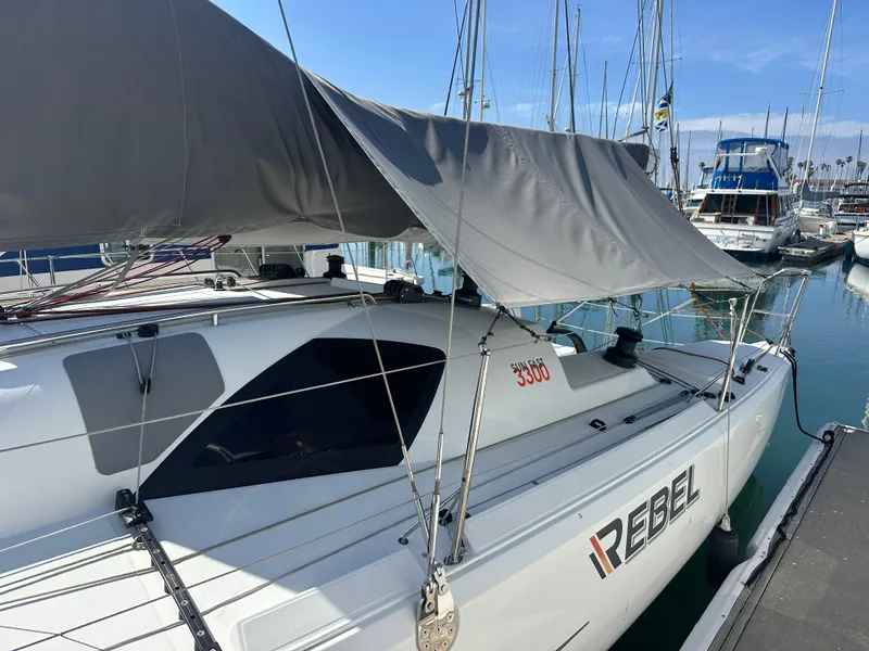 Slide: The Image of 2021 Jeanneau Sun Fast 3300 sailboat docked at marina, featuring "Rebel" branding. - 4