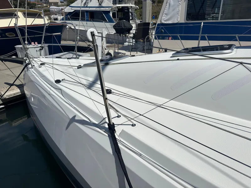 Slide: The Image of 2021 Jeanneau Sun Fast 3300 sailboat docked at marina, showcasing sleek design and rigging. - 5