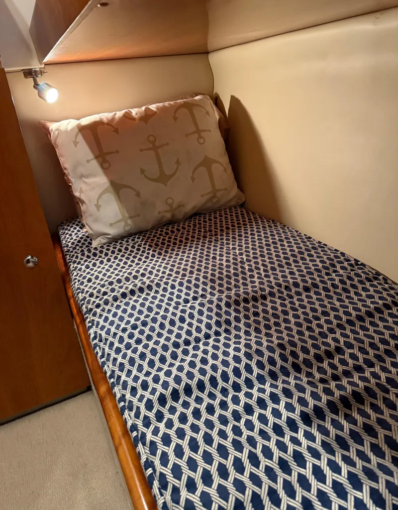 Slide: The Image of 2007 Riviera 3600 Sport Yacht cabin with patterned bedding and anchor-themed pillow. - 23