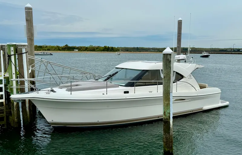 Slide: The Image of 2007 Riviera 3600 Sport Yacht docked in a serene marina setting. - 5