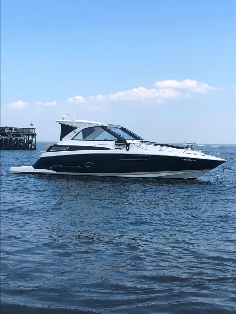 Slide: The Image of 2012 Regal 35 Sport Coupe boat on calm water under blue sky. - 1
