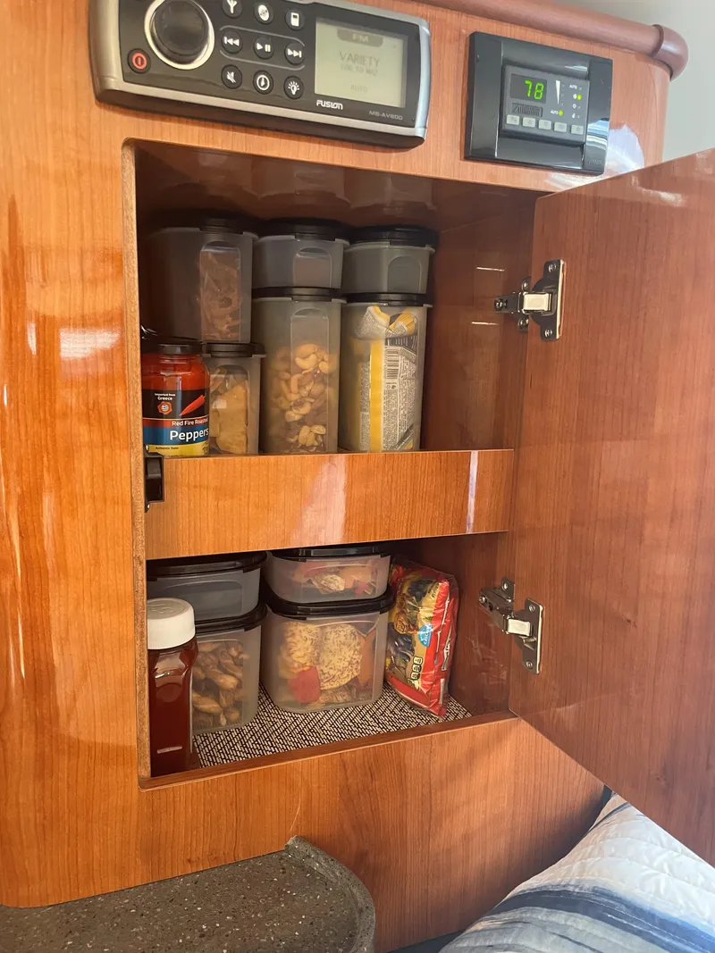 Slide: The Image of Cabinet storage in 2012 Regal 35 Sport Coupe, featuring organized food containers and control panels. - 11