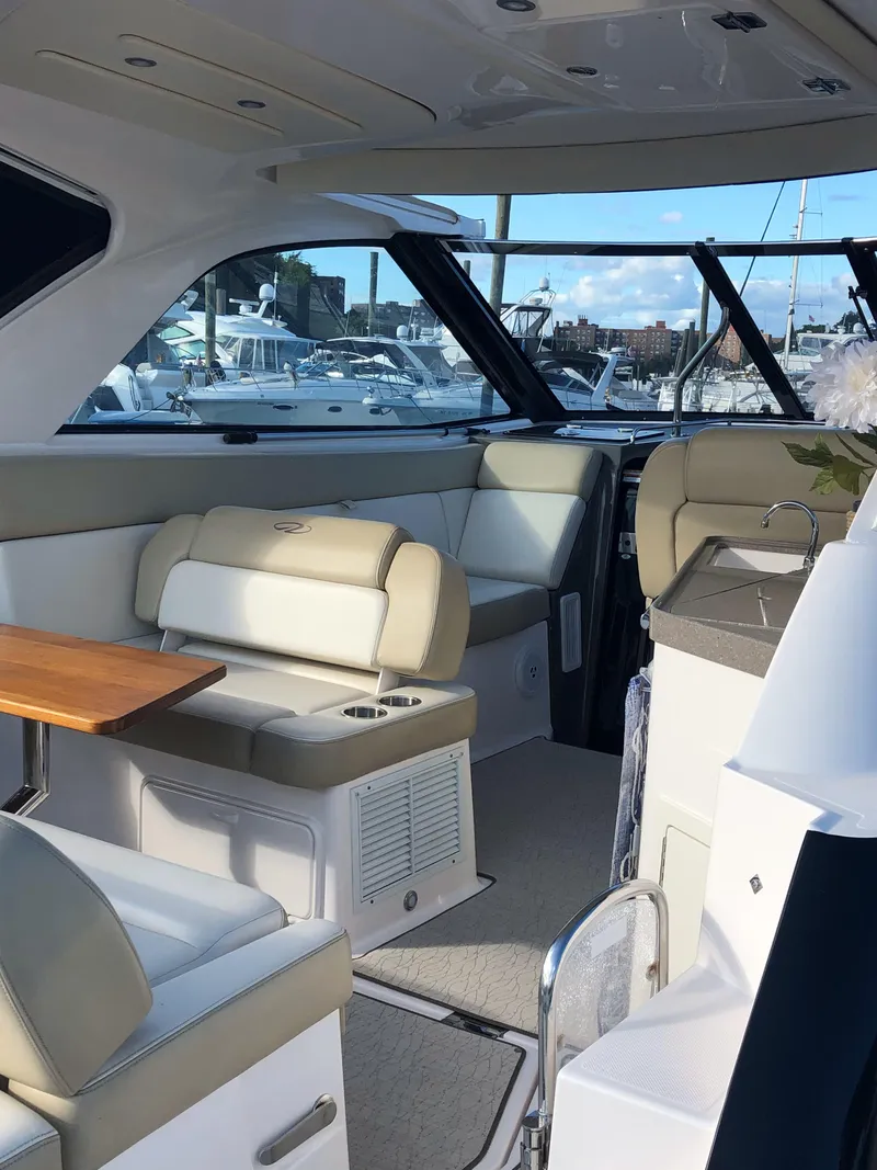 Slide: The Image of 2012 Regal 35 Sport Coupe interior with beige seating and wooden table, docked at marina. - 6