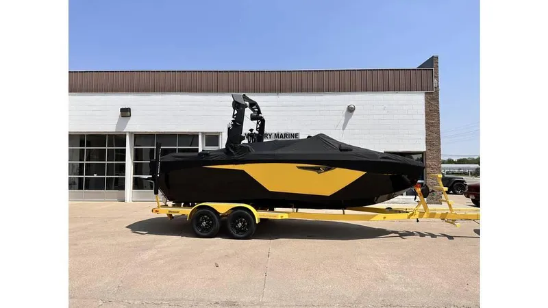 Slide: The Image of 2023 Nautique Super Air Nautique S21 boat on yellow trailer outside a building. - 2