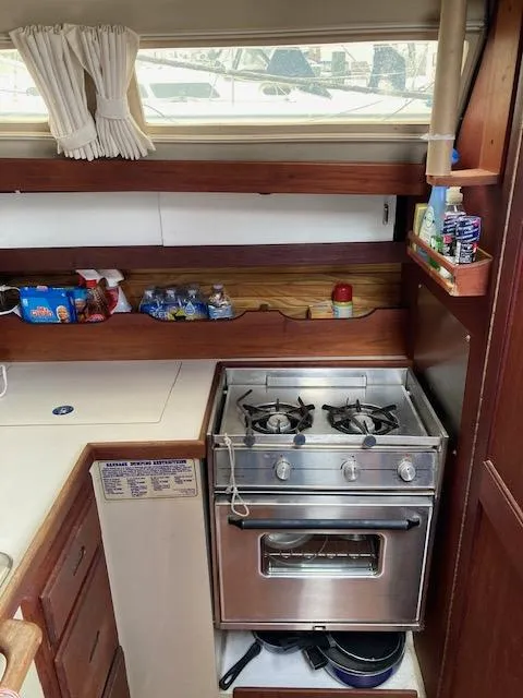 Slide: The Image of 1988 Catalina 34 yacht kitchen with stove, shelves, and storage. - 6