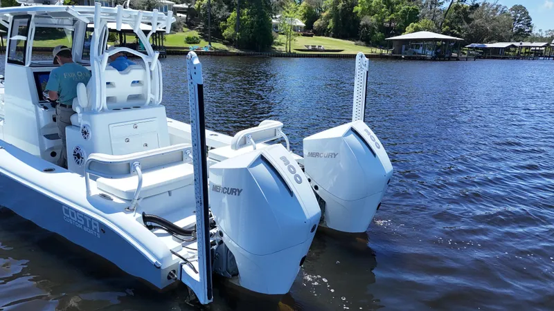 Slide: The Image of 2022 Costa Custom Boats 264 HC on a serene lake with dual Mercury engines. - 10