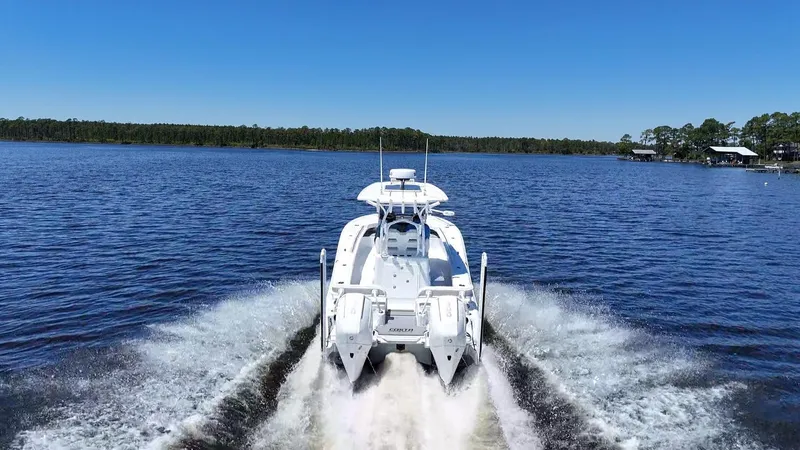 Slide: The Image of 2022 Costa Custom Boats 264 HC cruising on a serene lake under a clear blue sky. - 11