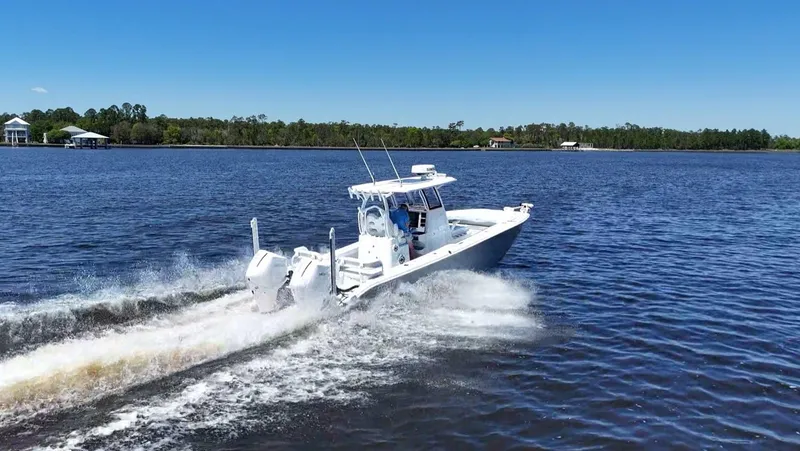 Slide: The Image of 2022 Costa Custom Boats 264 HC cruising on a serene lake under a clear blue sky. - 12