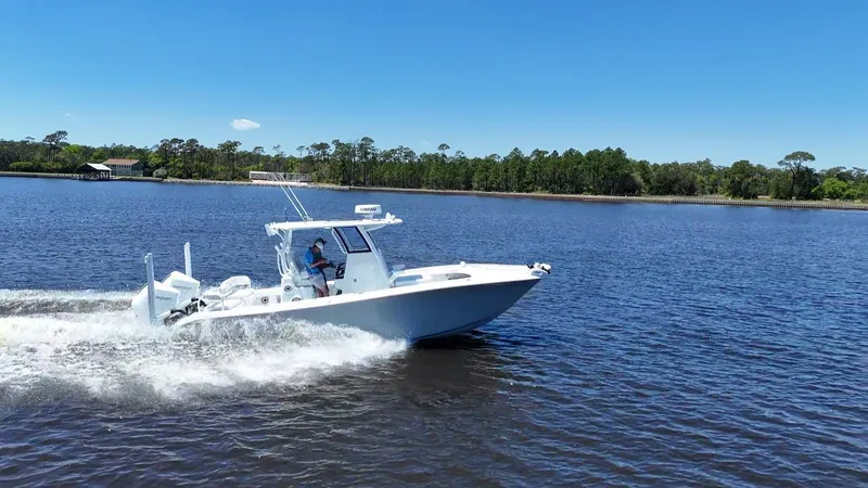 Slide: The Image of 2022 Costa Custom Boats 264 HC cruising on a serene lake under a clear blue sky. - 13