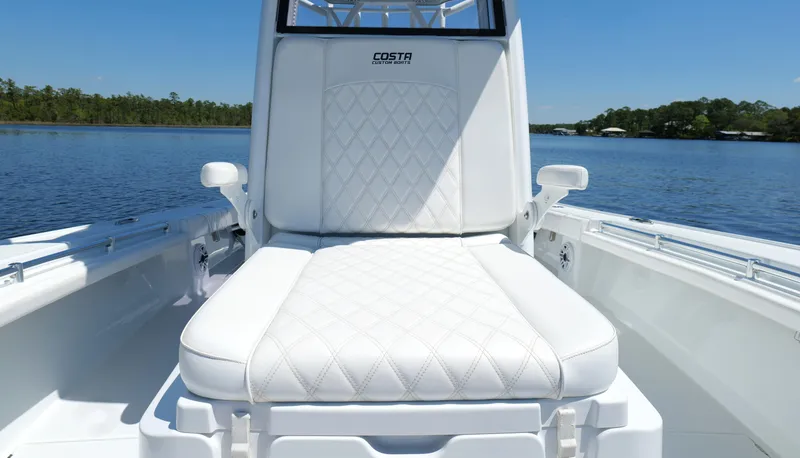 Slide: The Image of 2022 Costa Custom Boats 264 HC with white cushioned seating on a calm lake. - 39