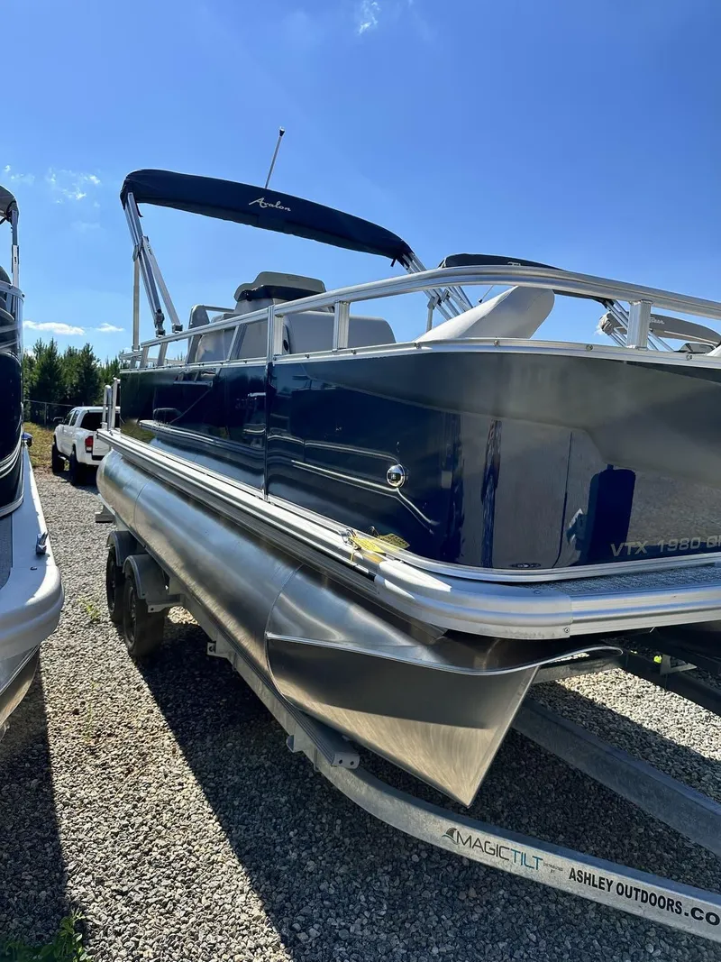 Slide: The Image of 2024 Avalon VTX Quad Fish pontoon boat on trailer, sunny day. - 1