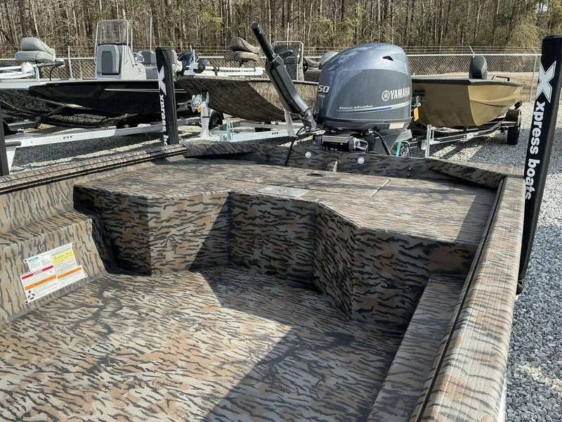 Slide: The Image of 2025 Xpress HD Series HD16DBX boat with Yamaha motor, camo design, parked outdoors. - 3