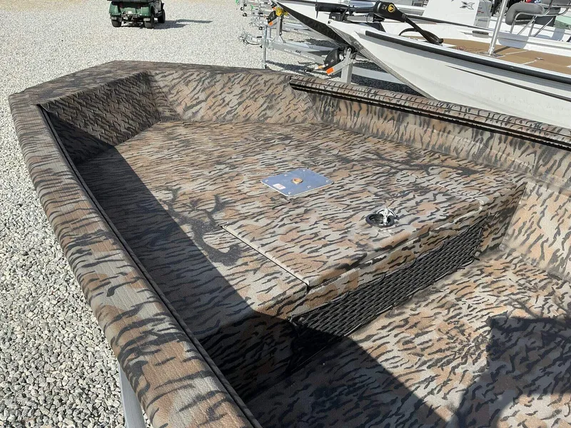 Slide: The Image of 2025 Xpress HD Series HD16DBX boat with camouflage interior, parked on gravel. - 4