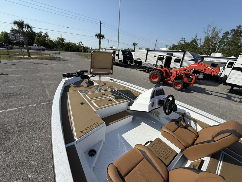 Slide: The Image of 2025 Xpress Hyper-Lift H18 Crappie boat with tan seating and control panel in parking lot. - 4