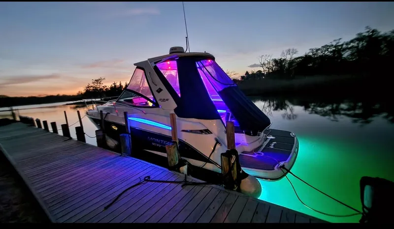 Slide: The Image of 2021 Monterey 335 Sport Yacht docked at sunset with vibrant LED lights. - 2