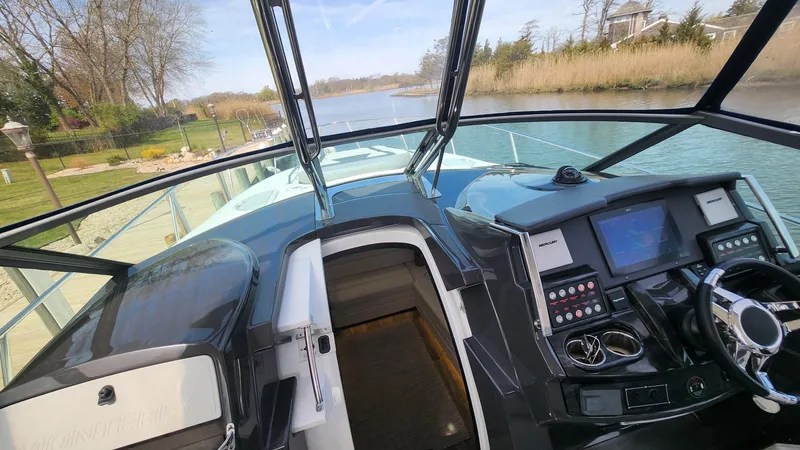 Slide: The Image of 2021 Monterey 335 Sport Yacht cockpit with modern controls, steering wheel, and scenic waterway view. - 21