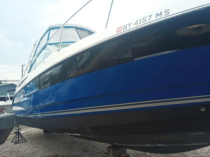 Slide: The Image of 2021 Monterey 335 Sport Yacht with blue hull, docked on land. - 5