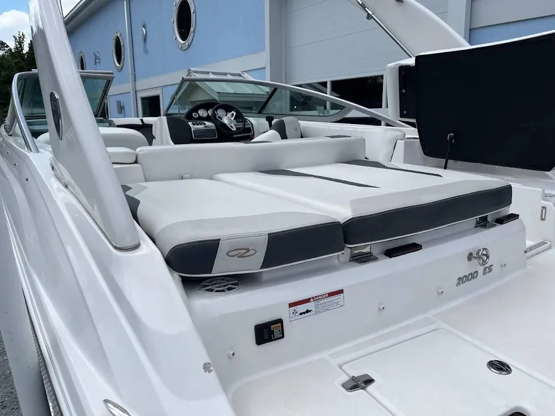 Slide: The Image of 2016 Regal 2000 ESX boat with white seating and modern dashboard, docked near a building. - 15