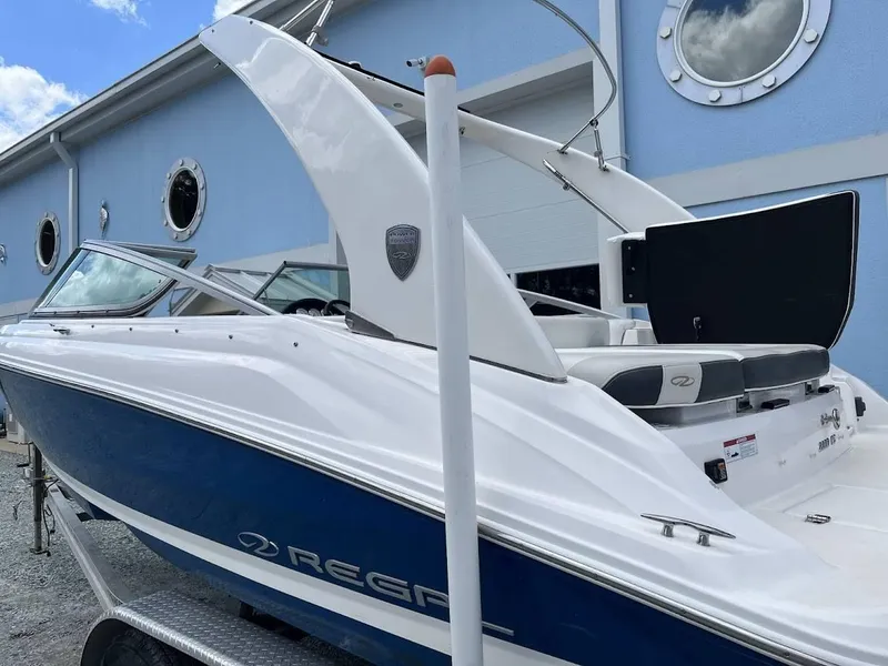 Slide: The Image of 2016 Regal 2000 ESX boat with blue and white exterior, parked near a building. - 16