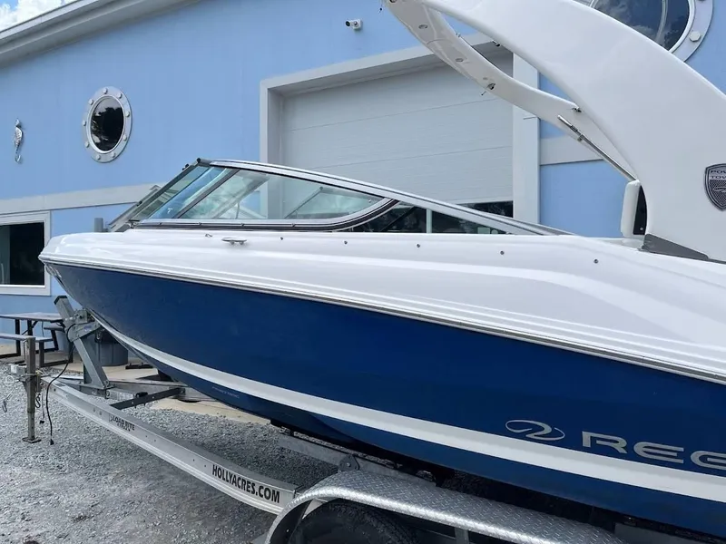 Slide: The Image of 2016 Regal 2000 ESX boat on trailer, blue and white, parked near a blue building. - 17