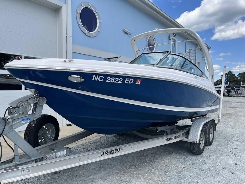 Slide: The Image of 2016 Regal 2000 ESX boat on trailer, parked outside a blue building under a cloudy sky. - 18