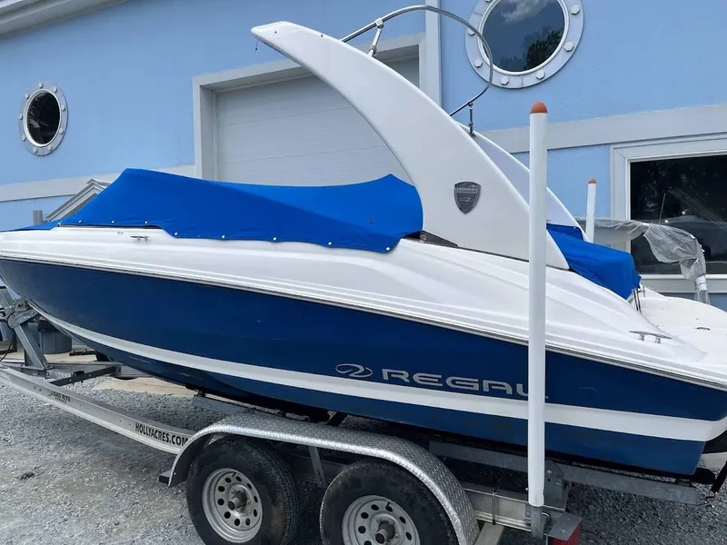 Slide: The Image of 2016 Regal 2000 ESX boat with blue cover on trailer, parked near a building. - 22