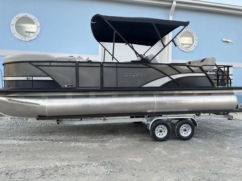 Slide: The Image of 2022 Sylvan L3 DLZ pontoon boat on trailer, parked outside a blue building. - 17