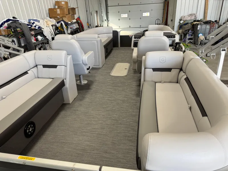 Slide: The Image of 2023 Sweetwater 2286 pontoon boat interior with plush seating in a storage facility. - 5