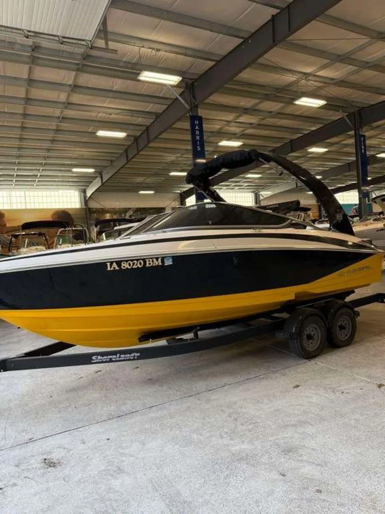 Slide: The Image of 2014 Regal 2300 boat with yellow and black design on a trailer in a warehouse. - 0