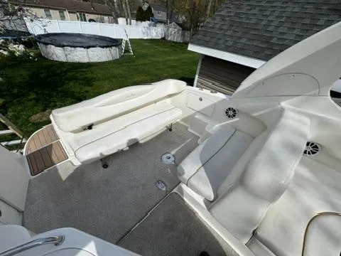 Slide: The Image of 2003 Sea Ray 280 Sundancer boat interior with white seating and outdoor setting. - 11