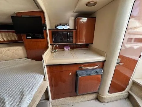 Slide: The Image of 2003 Sea Ray 280 Sundancer cabin with kitchenette, bed, and TV. - 16