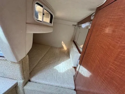 Slide: The Image of 2003 Sea Ray 280 Sundancer cabin interior with bed and wooden cabinetry. - 19