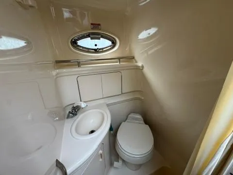 Slide: The Image of 2003 Sea Ray 280 Sundancer bathroom with sink, toilet, and porthole window. - 21