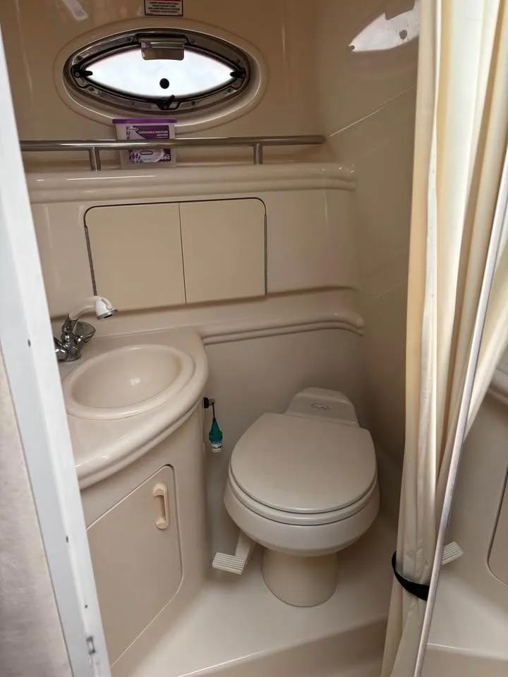 Slide: The Image of 2003 Sea Ray 280 Sundancer bathroom with sink, toilet, and porthole window. - 22