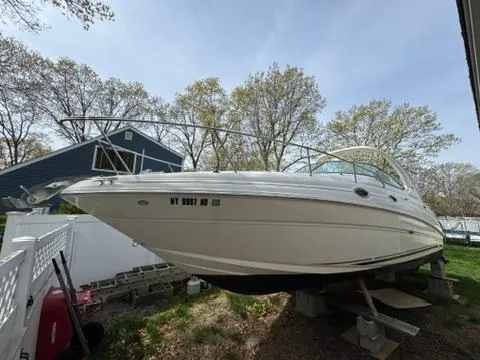 Slide: The Image of 2003 Sea Ray 280 Sundancer boat on blocks, surrounded by trees and a house. - 3