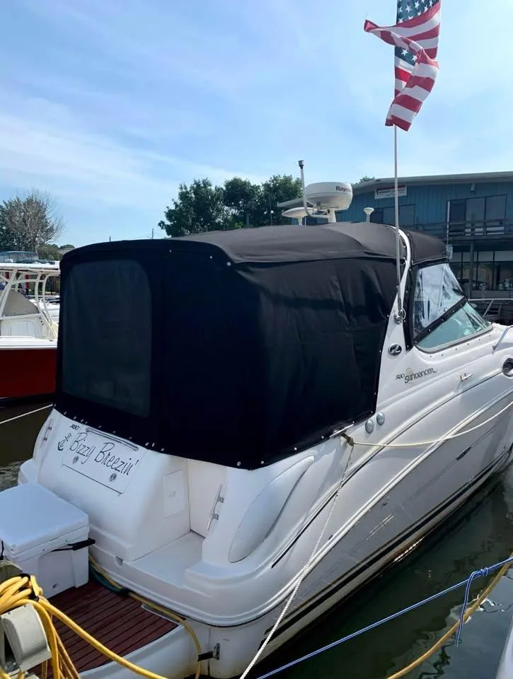Slide: The Image of 2003 Sea Ray 280 Sundancer docked with American flag, black canopy, and marina backdrop. - 8