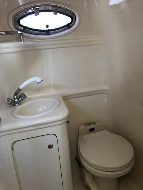 Slide: The Image of 2001 Sea Ray 260DA boat bathroom with sink, toilet, and porthole window. - 14
