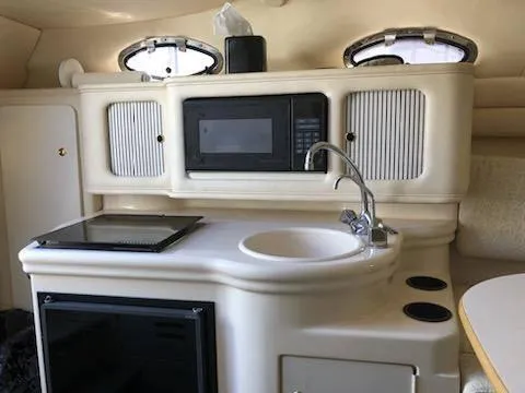 Slide: The Image of 2001 Sea Ray 260DA boat interior with kitchenette, featuring sink, microwave, and stove. - 19