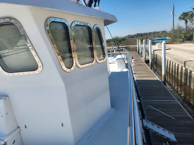 Slide: The Image of 1983 Custom 76 Trawler docked, showcasing windows and deck, with clear blue sky. - 16