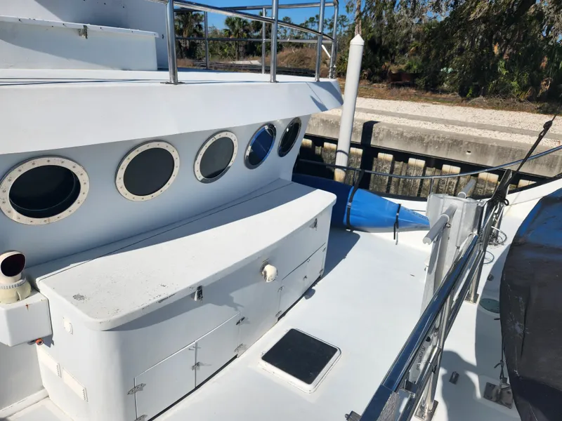 Slide: The Image of 1983 Custom 76 Trawler deck with portholes and railing, docked by a canal. - 17