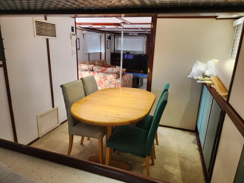 Slide: The Image of Dining area inside a 1983 Custom 76 Trawler, featuring a wooden table and chairs. - 40