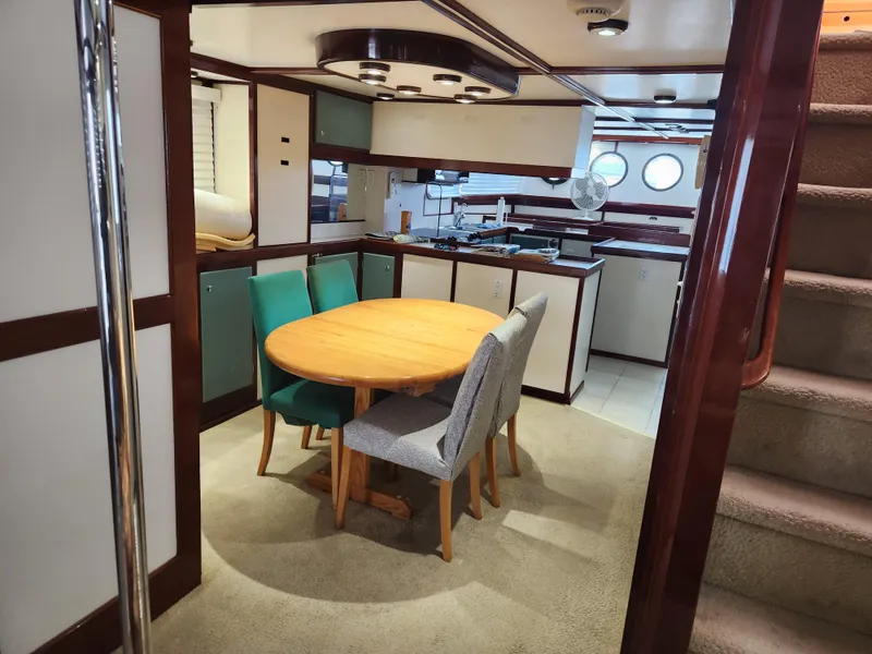 Slide: The Image of Interior of 1983 Custom 76 Trawler with dining area and kitchen, featuring round table and chairs. - 41