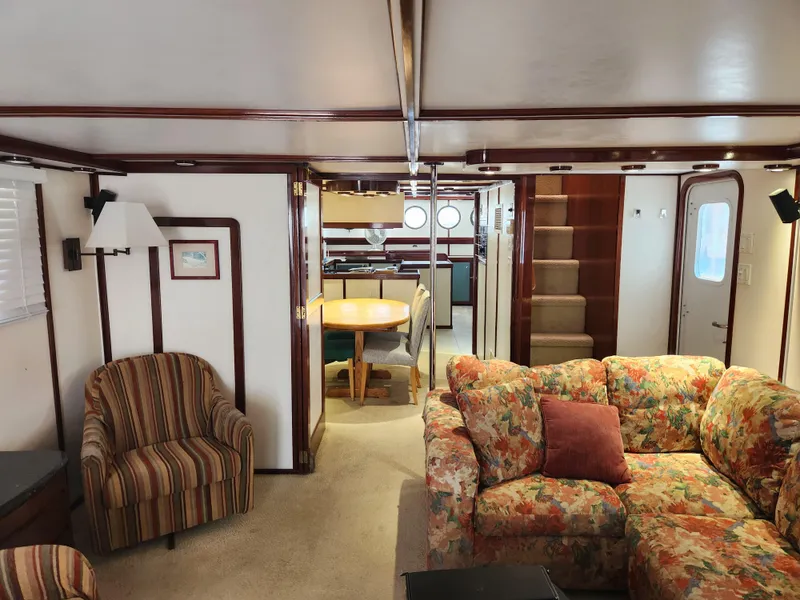 Slide: The Image of Interior of 1983 Custom 76 Trawler with floral sofa, striped chair, and dining area. - 42