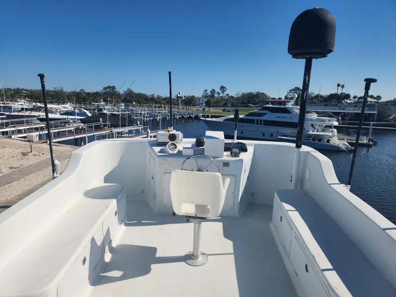 Slide: The Image of 1983 Custom 76 Trawler's upper deck with seating, helm, and marina view. - 6