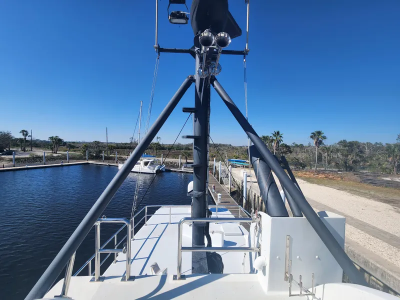Slide: The Image of 1983 Custom 76 Trawler docked, showcasing deck and mast under clear blue sky. - 9