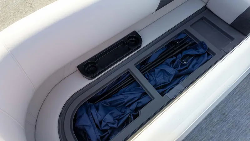 Slide: The Image of 2025 Bennington 20 SL boat seat storage compartment with cup holders and blue cover. - 14