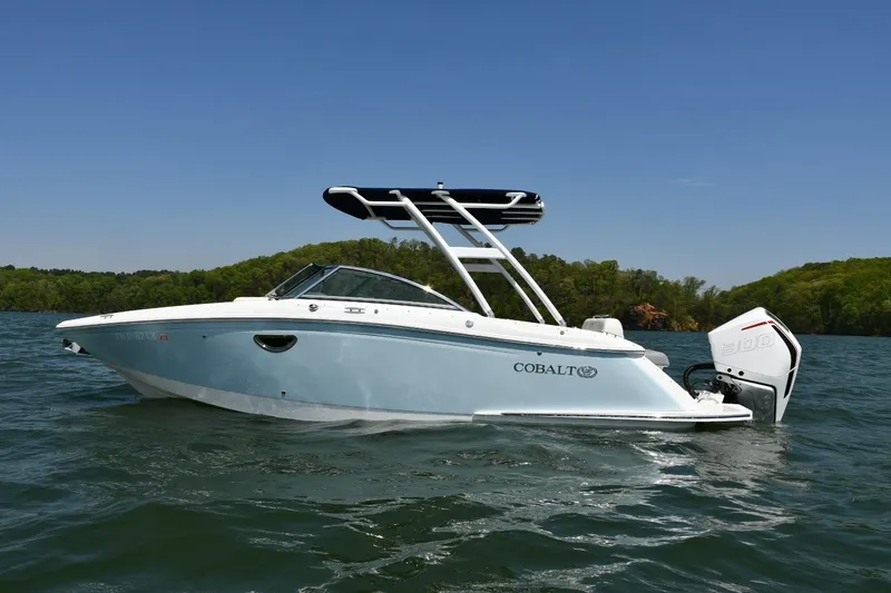 Slide: The Image of 2019 Cobalt 25SC boat on a lake, clear sky, lush green shoreline. - 0