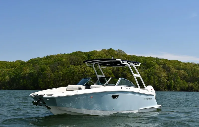 Slide: The Image of 2019 Cobalt 25SC boat on a lake with lush green forest background. - 2