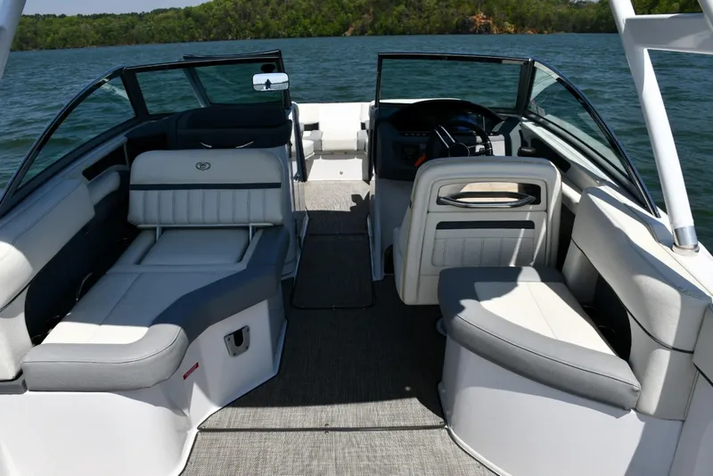 Slide: The Image of 2019 Cobalt 25SC boat interior with seating, on a lake with lush green shoreline. - 8