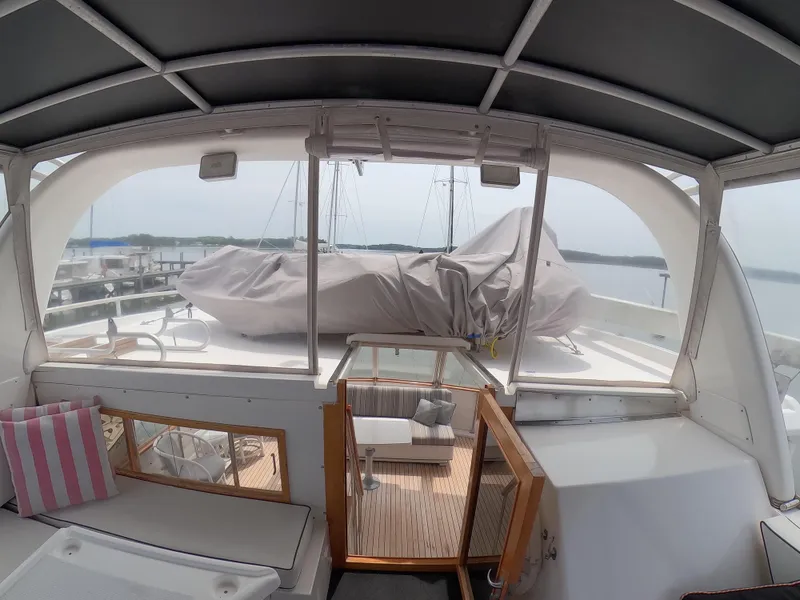 Slide: The Image of 1995 Jefferson 48 Rivanna yacht interior with covered deck, seating, and scenic marina view. - 10